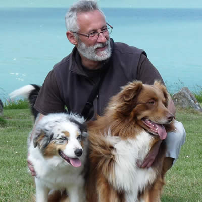 laurent loizzo in front of a lake with two australian shepherds